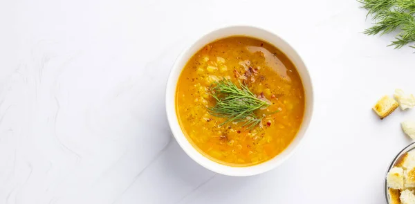 Red lentil soup with ingredients on a light background. Traditional Turkish or Arabic spicy lentil and vegetable soup, healthy vegan food. Top view, copyspace.