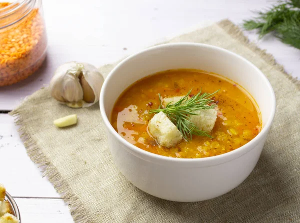 Red lentil soup with ingredients on a light background. Traditional Turkish or Arabic spicy lentil and vegetable soup, healthy vegan food. Side view