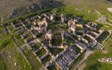 Hierapolis Antik Kenti ve Türkiye 'nin Denizli kentindeki ünlü Pamukkale travertinlerinin insansız hava aracı görüntüsü, yukarıdan antik harabeleri, Roma tiyatrosunu, sütunları ve manzarayı gösteriyor.