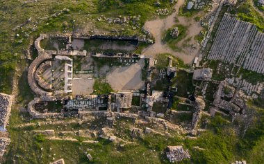 Hierapolis Antik Kenti ve Türkiye 'nin Denizli kentindeki ünlü Pamukkale travertinlerinin insansız hava aracı görüntüsü, yukarıdan antik harabeleri, Roma tiyatrosunu, sütunları ve manzarayı gösteriyor.