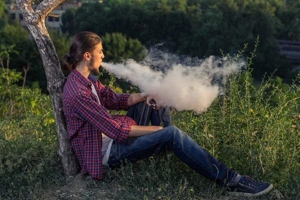 Schöner junger Mann, der elektronische Zigarette raucht. — Stockfoto