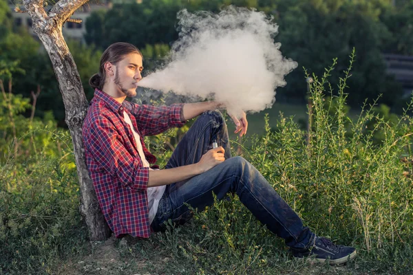 Beau jeune homme fumant cigarette électronique . — Photo