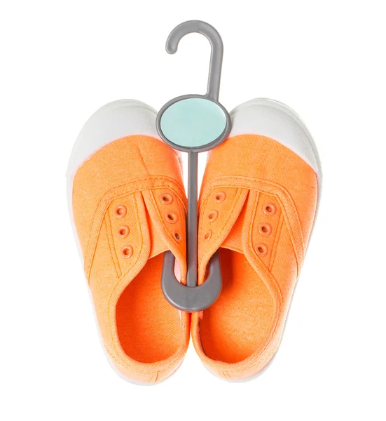 Baby meisje oranje sneakers op kunststof hanger. — Stockfoto