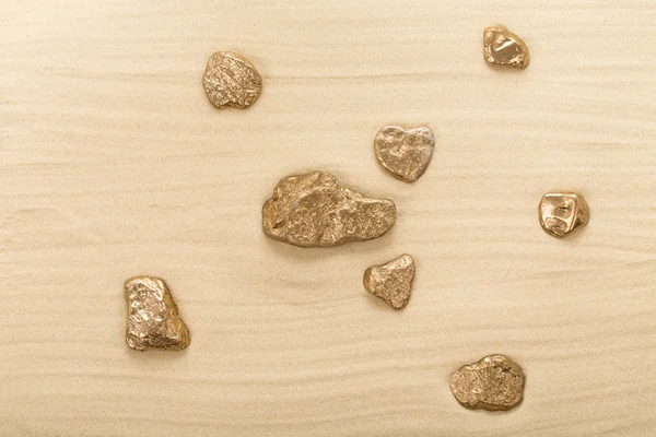 Golden stones on waved sand. — Stock Photo, Image