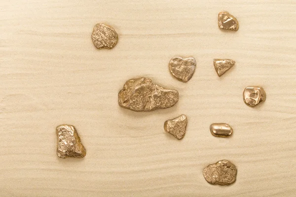 Golden stones on waved sand. — Stock Photo, Image