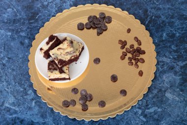 Cheesecake brownie and roasted coffee beans. Blue marble background. Close-up.