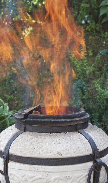 Flames leap out of the tandoor.