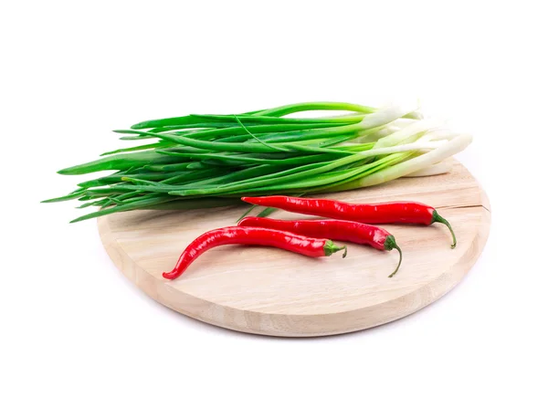 Red peppers and scallions on the wooden board. — Stock Photo, Image