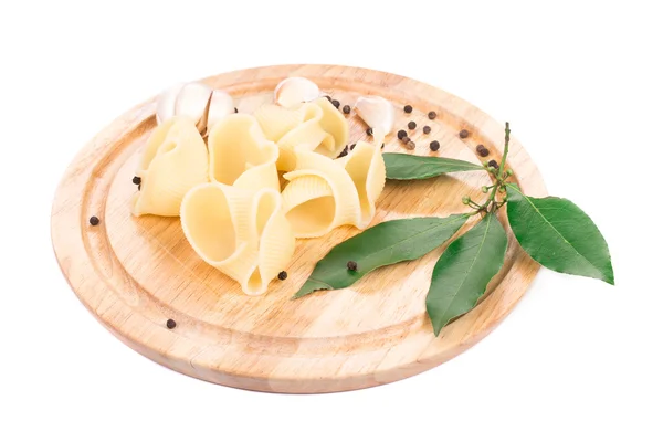 Italian pasta shells on a wood plate. — Stock Photo, Image