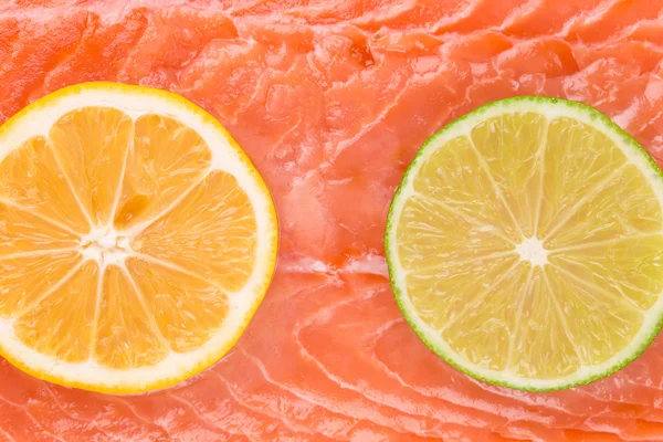 Lemon and lime on salmon fillet. Macro. — Stock Photo, Image