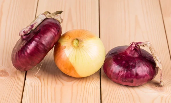 Red and golden onions on wooden platter. — Stock Photo, Image