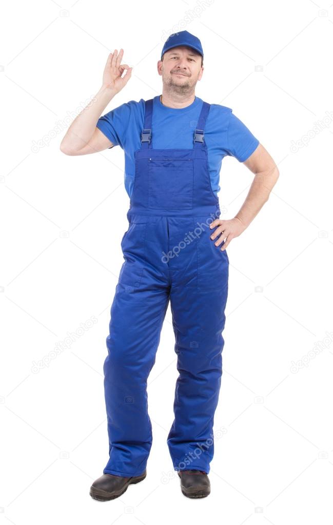 Man in blue overalls shows ok sign.
