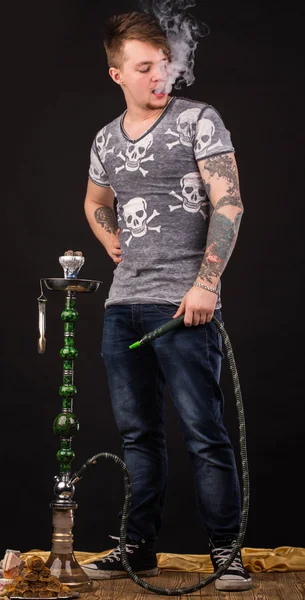 Tattooed man smoking traditional hookah. — Stock Photo, Image