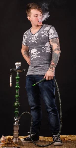 Tattooed man smoking traditional hookah. — Stock Photo, Image