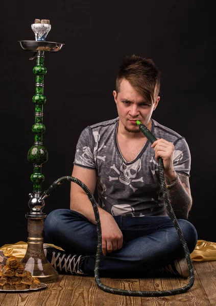 Tattooed man smoking traditional hookah. — Stock Photo, Image