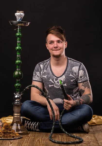 Tattooed man smoking traditional hookah. — Stock Photo, Image