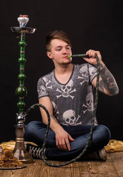 Tattooed man smoking traditional hookah. — Stock Photo, Image