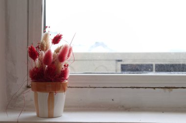 Pencere kenarında suni çiçekli saksılar. Bir apartmanın girişinde yer alıyor. Yakın plan..