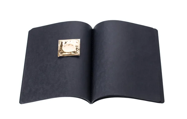 Black cardboard notebook with golden condom — Stock Photo, Image