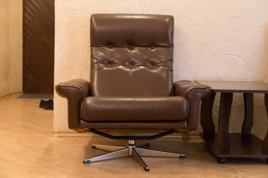 Gerçek deriden yapılmış bir ofis sandalyesinin ön görüntüsü. Bu koltuk modern bir apartmanın koridorunda yer almaktadır..