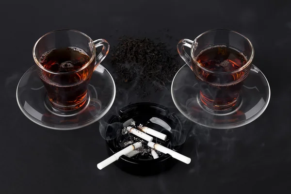 Tazze di tè con sigarette — Foto Stock
