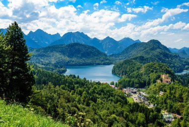 Alpsee ve Ludwig II Kalesi Hohenschwangau, mavi gökyüzü, Neuschwanstein yakınlarındaki dağları görüyor. Fussen, Bavyera, Bayern, Almanya.