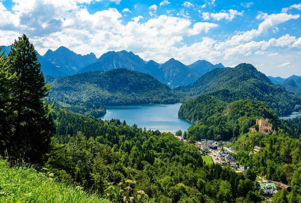 Alpsee ve Ludwig II Kalesi Hohenschwangau, mavi gökyüzü, Neuschwanstein yakınlarındaki dağları görüyor. Fussen, Bavyera, Bayern, Almanya.