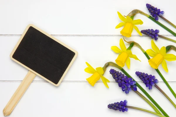 Garden sign on wooden surface and spring flowers — Stock Photo, Image