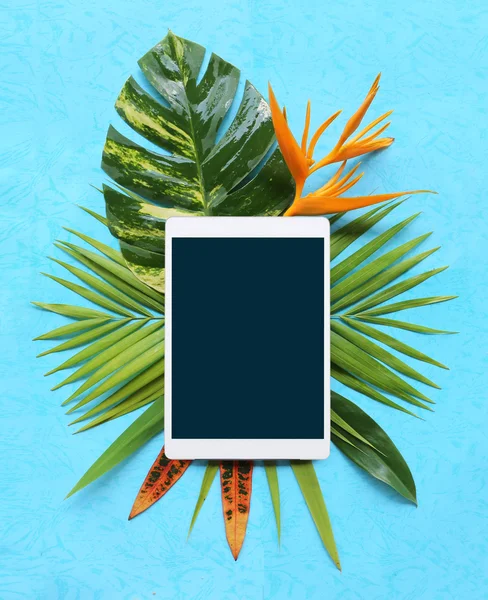 Plantas tropicais com comprimido sobre fundo azul — Fotografia de Stock