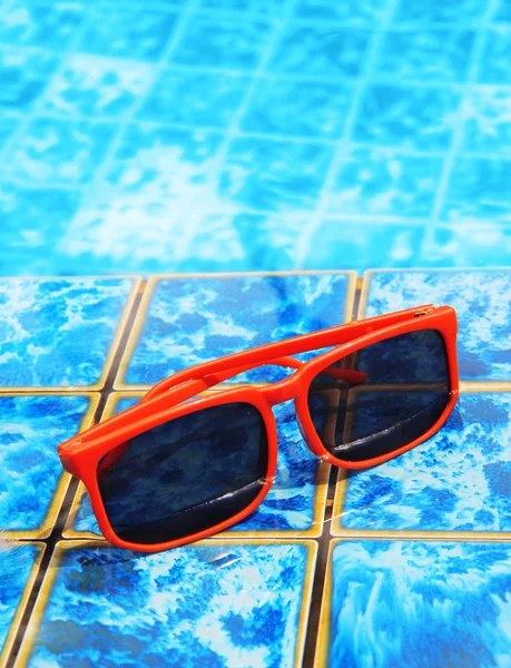 Sonnenbrille im Pool mit blauem Wasser — Stockfoto