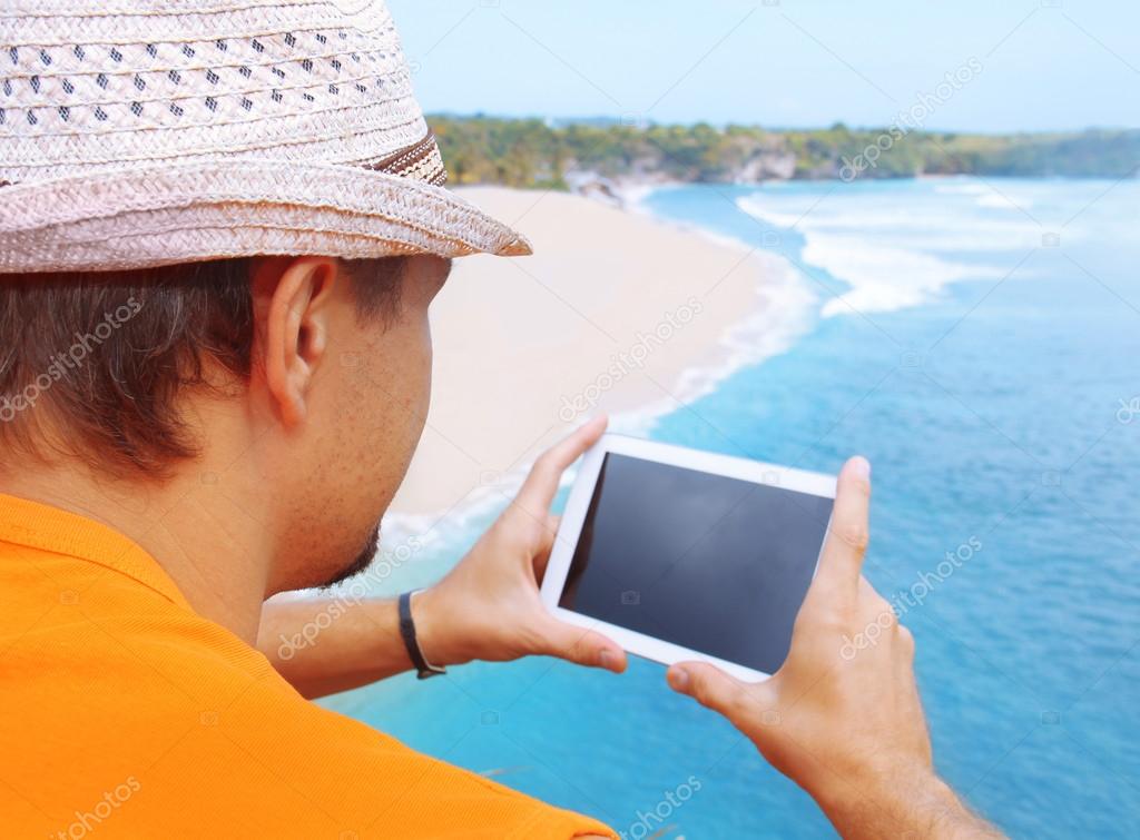 A man with tablet in hand on the beach