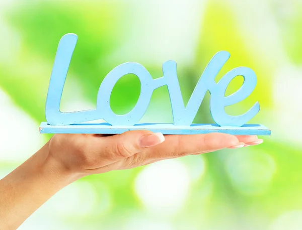 Female hand holding a Wooden signboard love — Stock Photo, Image