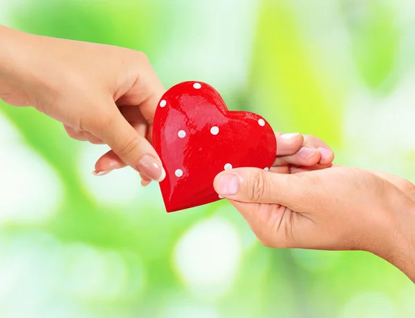 Man and woman holding red heart in hands — Stock Photo, Image