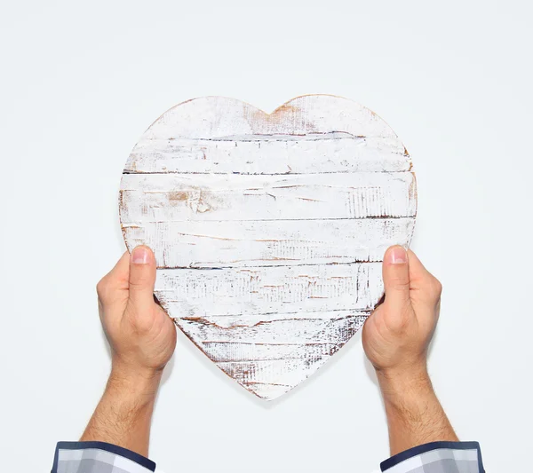 Mannelijke hand met een houten hart — Stockfoto