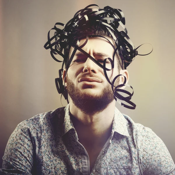 Divertente ritratto di uomo barbuto con film analogico sopra la testa — Foto Stock
