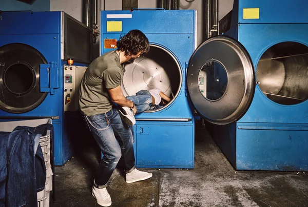 Pareja joven jugando en una lavandería industrial — Foto de Stock