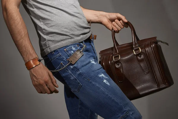 Genç adam bir deri çanta taşıyor