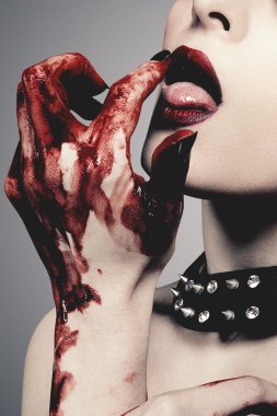 Gri arka plan karşı kan seksi genç kadın yalıyor