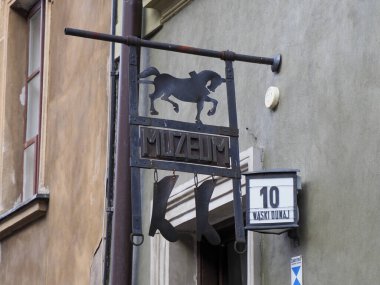 Açık kahverengi bir duvarda, bir bar ya da restoran için üzerinde at silueti olan koyu metal tarihi bir levhanın yakın çekimi..