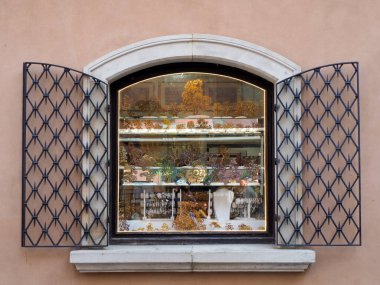 Polonya 'nın başkenti Varşova' da desenli pembe bir duvarda dekoratif metal ızgaralı ve açık kepenkli zarif bir pencere..