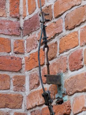 Yıpranmış, kırık, kırmızı tuğla bir duvara yakın çekim. Büyük, koyu metal bir çapa ile güçlendirilmiş..