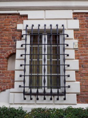 Varşova Eski Kasabası 'nda parmaklıklı penceresi ve dekoratif çerçevesi olan beyaz bir duvarın yakın çekimi.