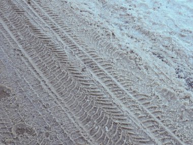 Ayrıntılı çapraz lastik izi yolda taze beyaz kara basılmış.