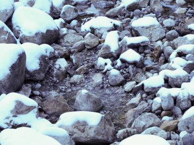 Dağdaki derenin suyu, kış ormanlarında karlı kayaların arasından akıyor..