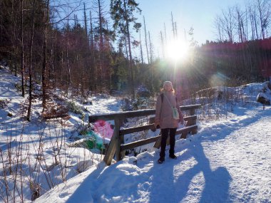 Parlak kış güneşi, karlı bir vadide, karanlık dağ yamacının ardında yükseliyor.
