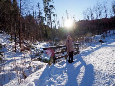 Parlak kış güneşi, karlı bir vadide, karanlık dağ yamacının ardında yükseliyor.