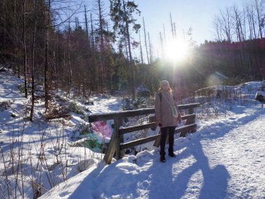 Parlak kış güneşi, karlı bir vadide, karanlık dağ yamacının ardında yükseliyor.