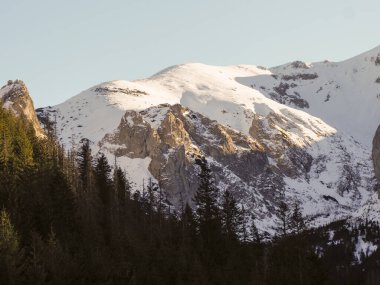 Parlak bir kış öğleden sonrası boyunca kayalık dağ zirvelerinin taze beyaz karla kaplı yakın çekimi.