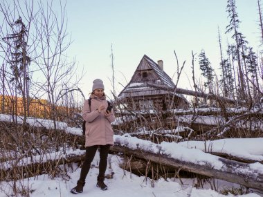 Güler yüzlü kadın gezgin dışarıdaki karlı bir ormanda seyyar bir cihaz kullanıyor..