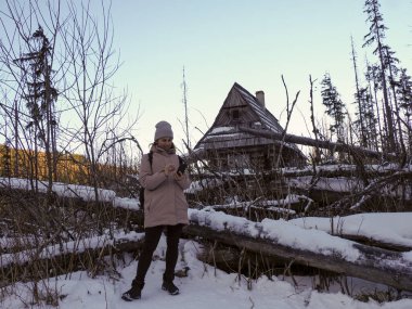 Karlı dağlarda seyrüsefer için akıllı telefon uygulaması kullanan kışlık kıyafetli genç bir kadın..